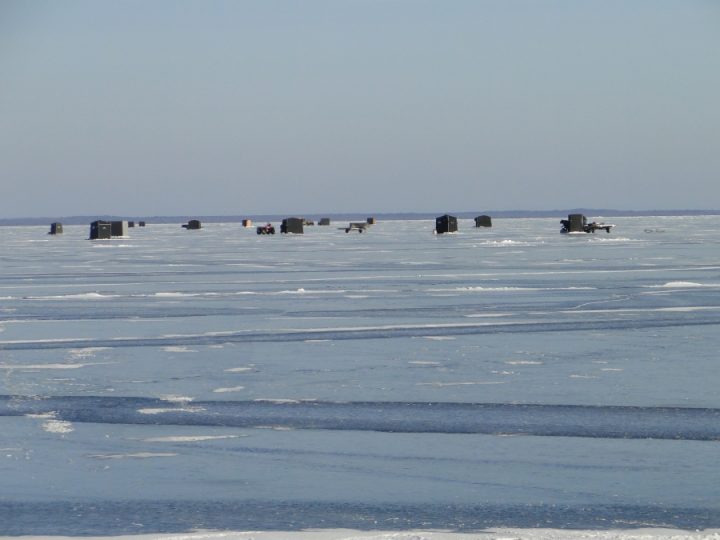 Ice fishing shanties scattered across frozen lake in winter