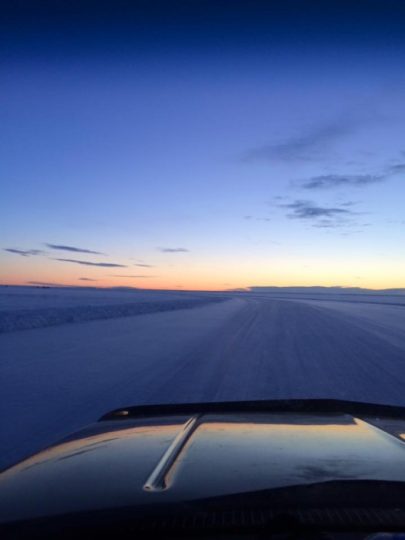 Snowy road at dusk viewed from vehicle dashboard