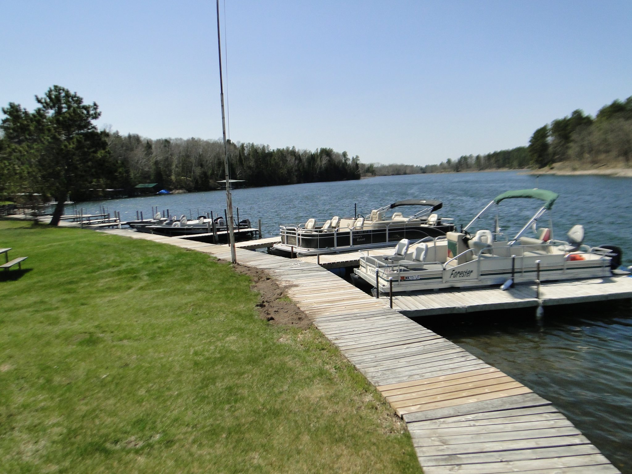 Pontoon boats docked at a lakeside wooden pier