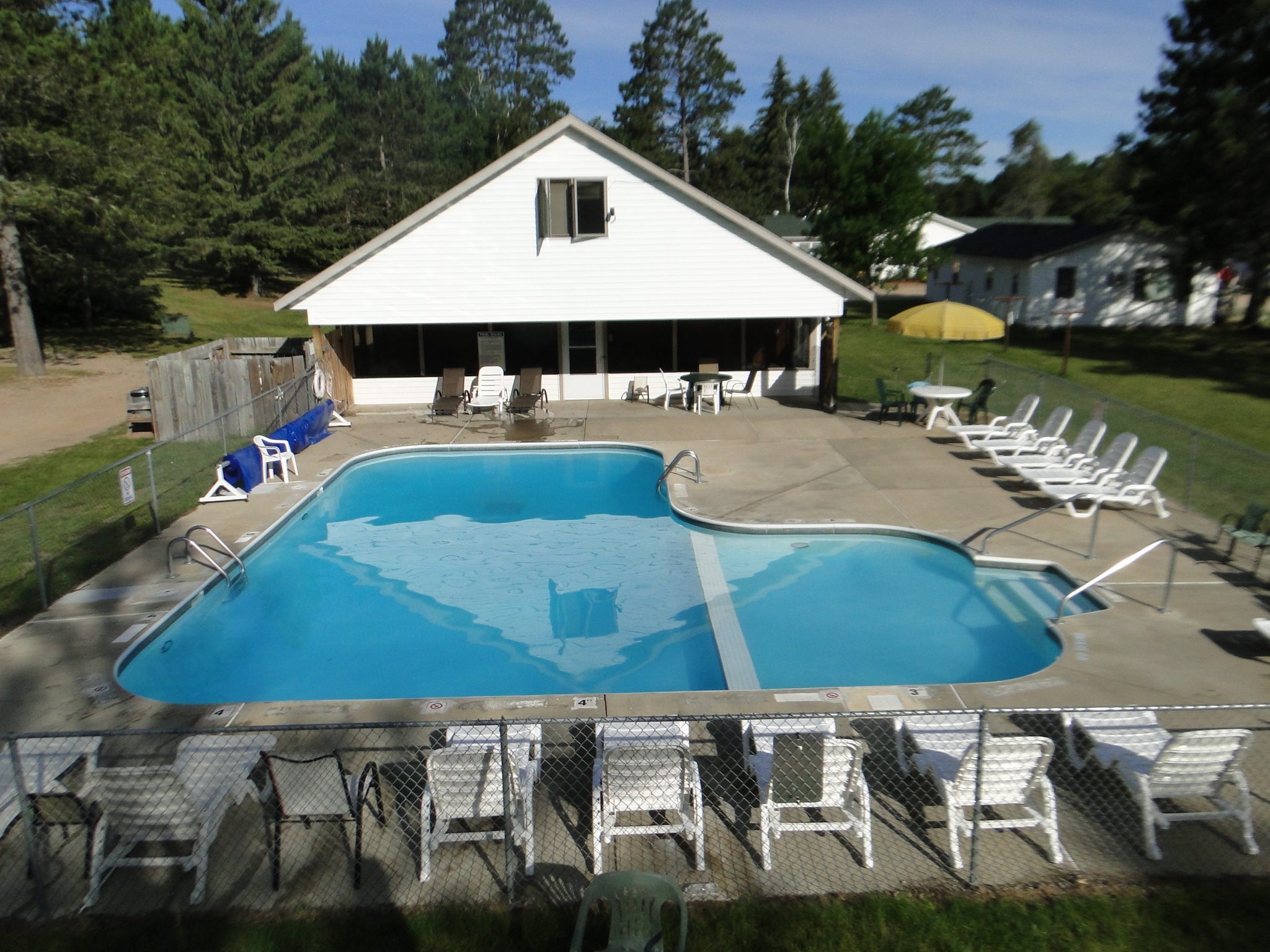 Outdoor resort pool with lounge chairs and white clubhouse