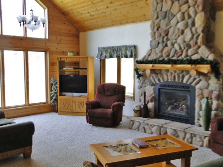 Cozy cabin living room with stone fireplace and wood ceiling