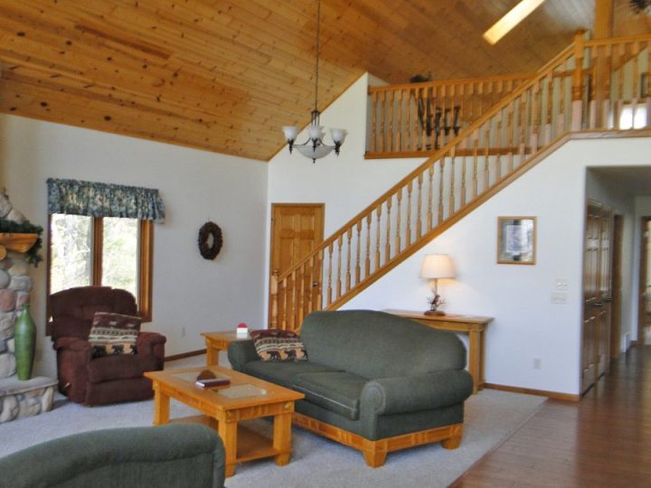 Cozy cabin living room with vaulted wood ceiling and staircase