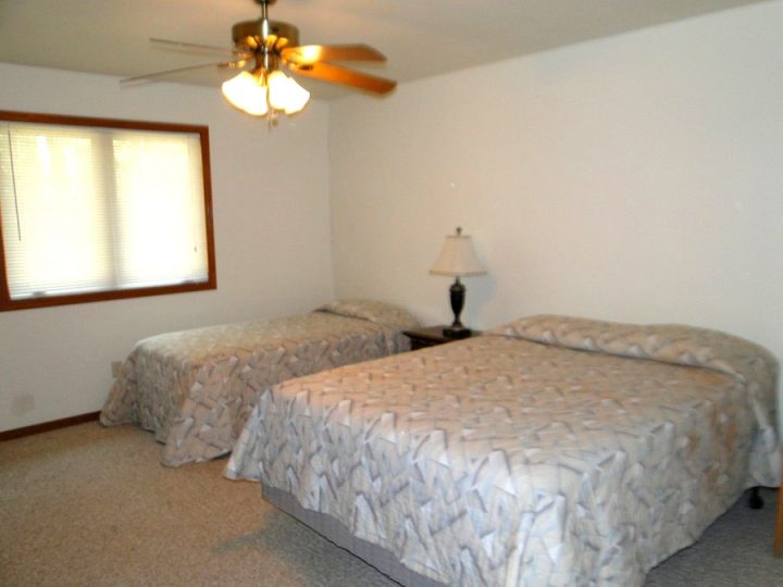Simple bedroom with two beds and ceiling fan