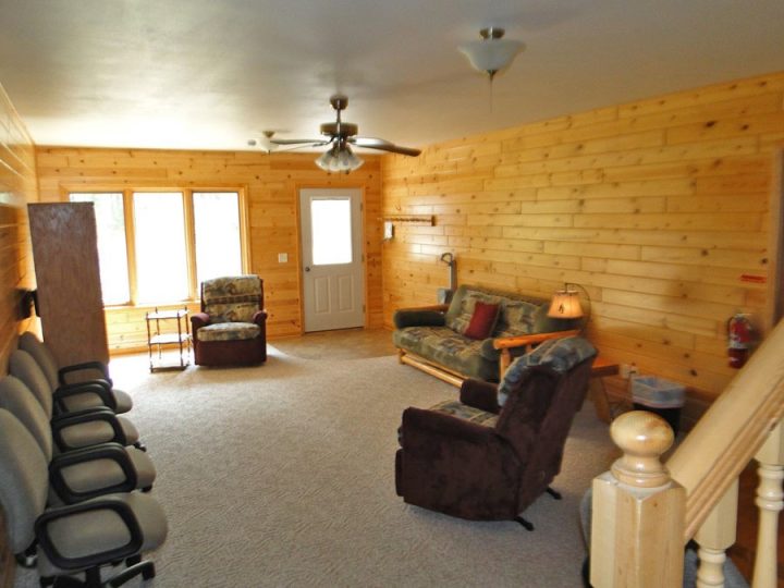 Cozy log cabin living room with mixed seating and ceiling fan