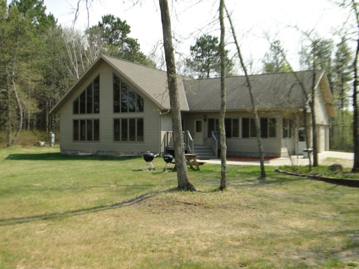 A-frame cabin surrounded by trees with outdoor grills