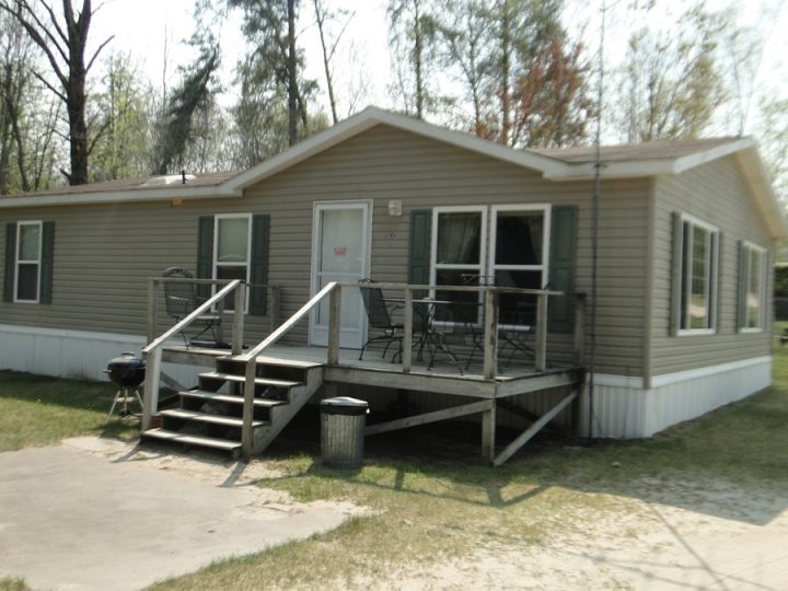 Gray mobile home with wooden deck and outdoor furniture