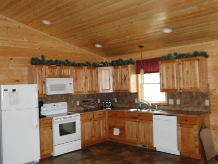 Rustic log cabin kitchen with pine wood cabinets and white appliances