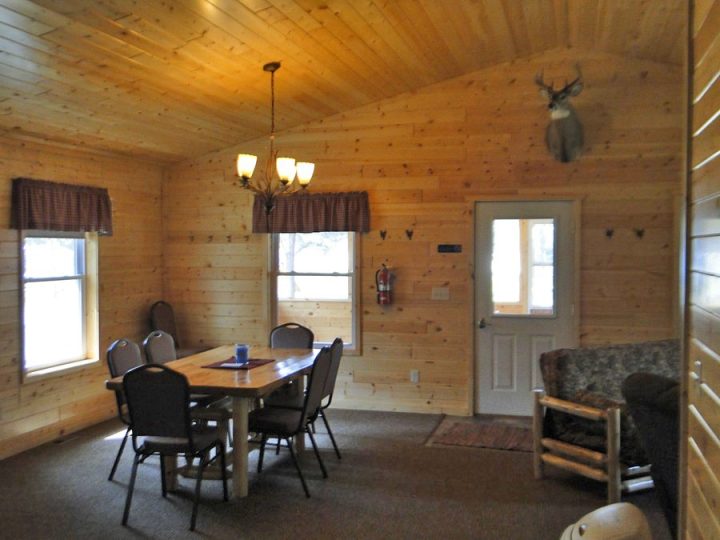 Rustic wooden cabin interior with dining table and deer mount