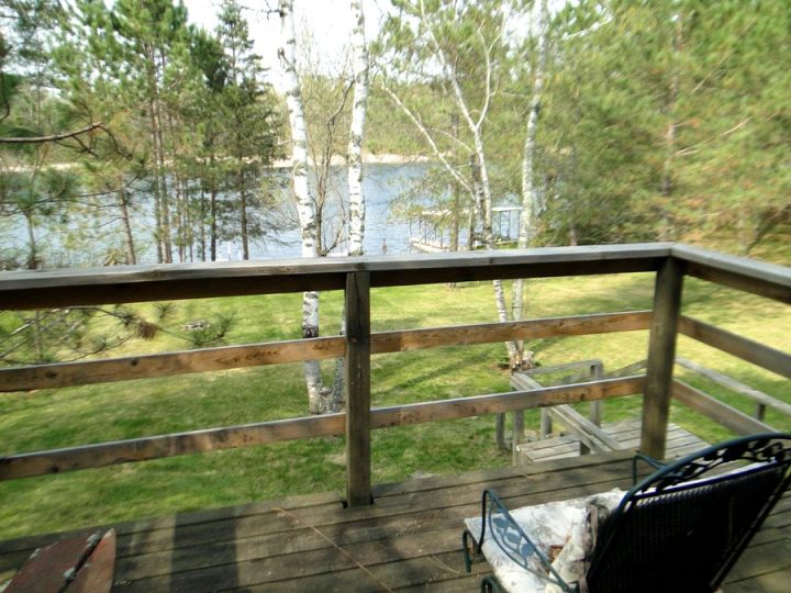 Wooden deck overlooking a serene lake surrounded by trees