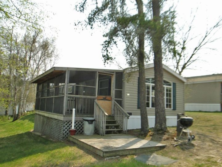 Mobile home with screened porch and wooden deck outdoors