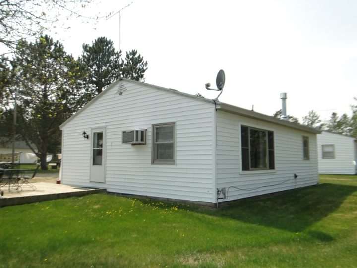 Small white house with satellite dish and green lawn