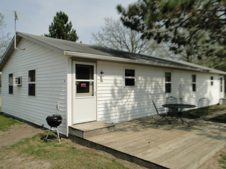 White ranch-style house with wooden deck and outdoor grill