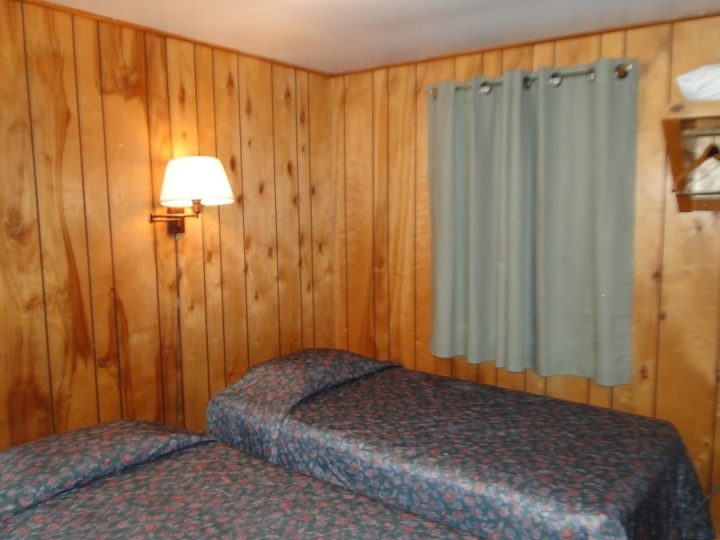 Rustic motel room with wood paneling and two beds
