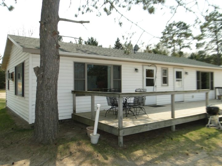 White ranch house with wooden deck and patio furniture
