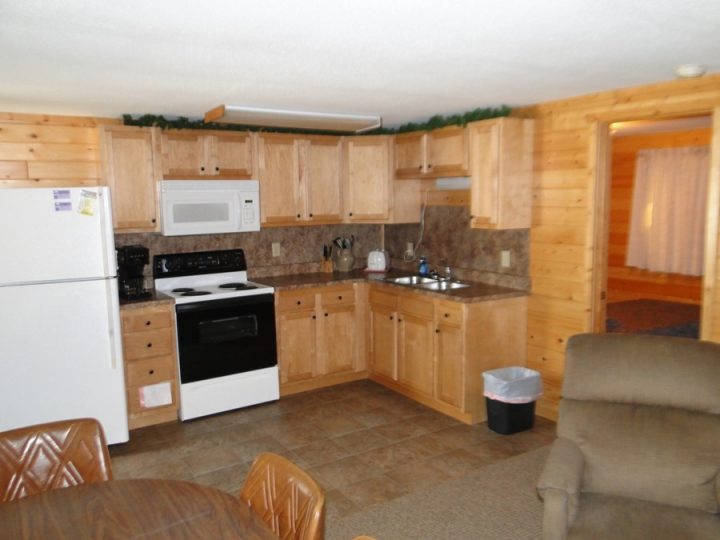 Cozy log cabin kitchen with wood cabinets and appliances