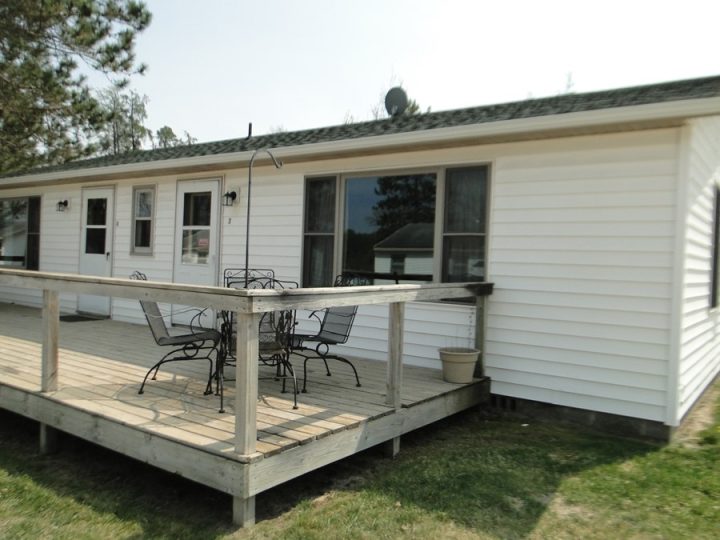 White ranch house with wooden deck and patio furniture