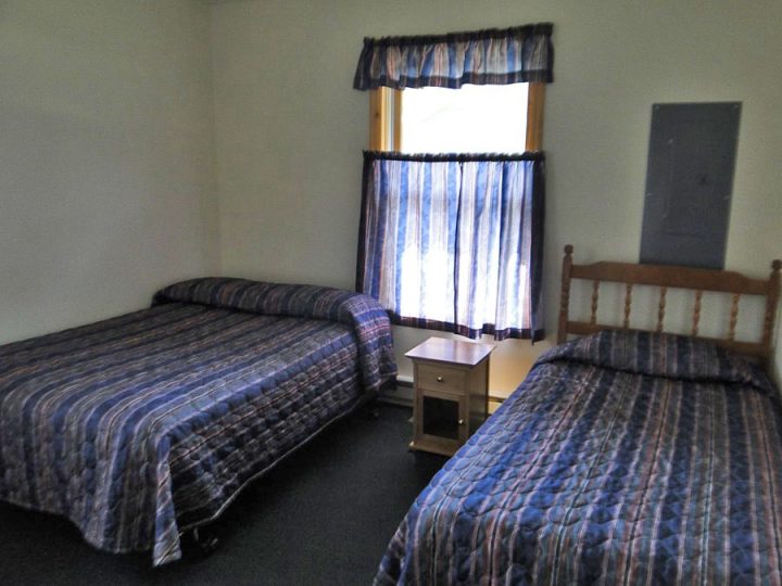 Simple motel room with two beds and blue plaid bedding