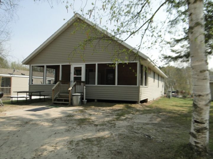 Small beige cottage with screened porch and wooden deck