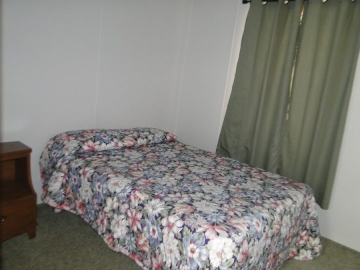 Small bedroom with floral bedspread and green curtains