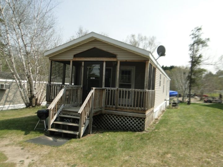 Small mobile home with wooden deck and screened porch