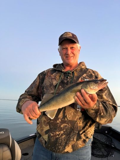 Smiling angler holding a walleye fish on a boat