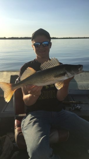 Angler proudly holding a large walleye fish on boat