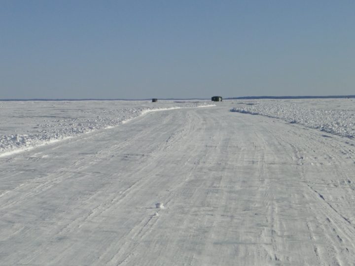 Frozen ice road stretching across snowy landscape in winter