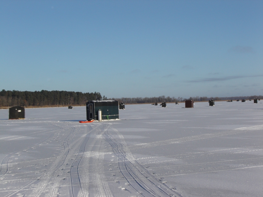 Ice fishing shanties scattered across a frozen lake in winter