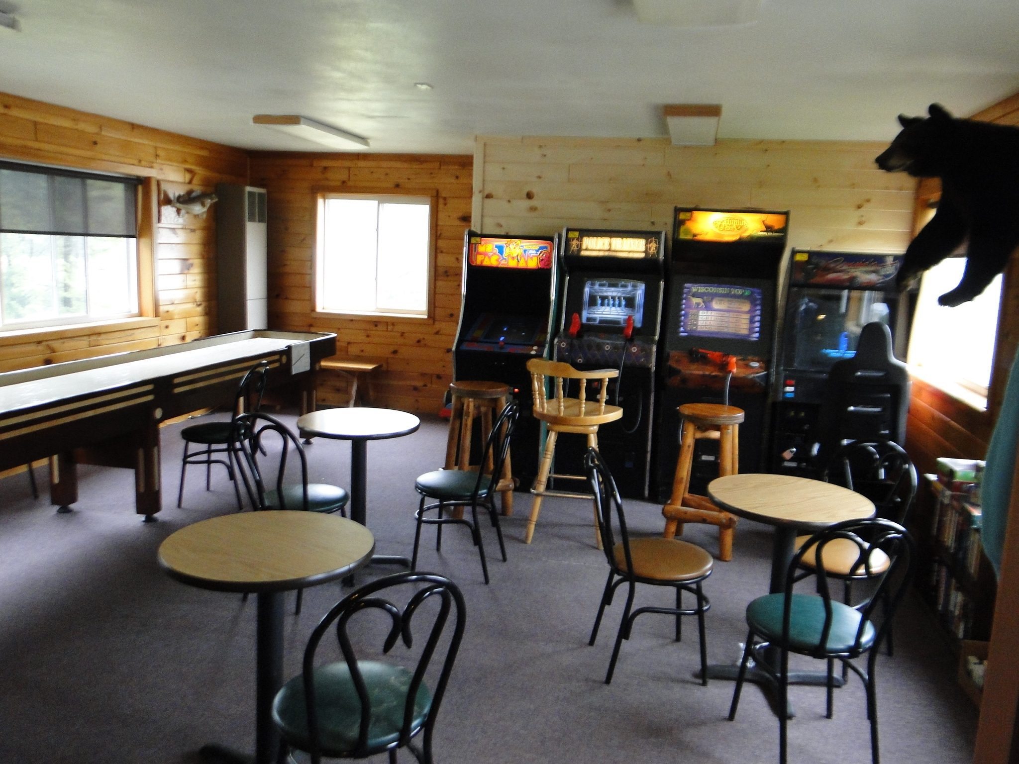 Rustic lodge game room with arcade machines and shuffleboard