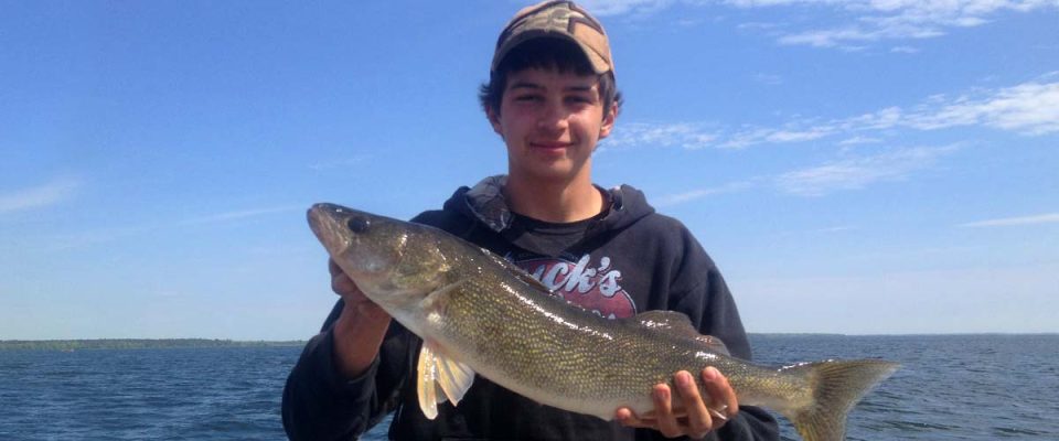 Young angler proudly holding a large walleye fish