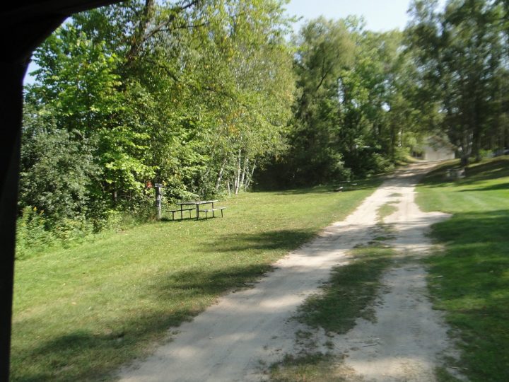 Gravel path through green park with picnic table and trees