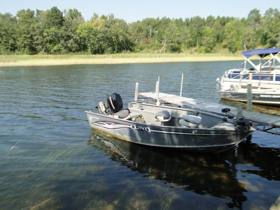 Lund fishing boat docked at a calm lake marina